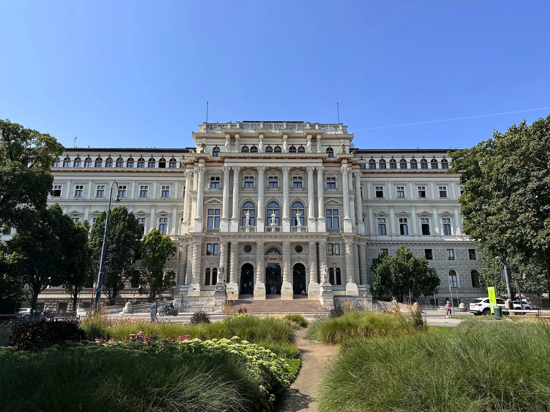 Un grand bâtiment historique derrière un jardin fleuri.