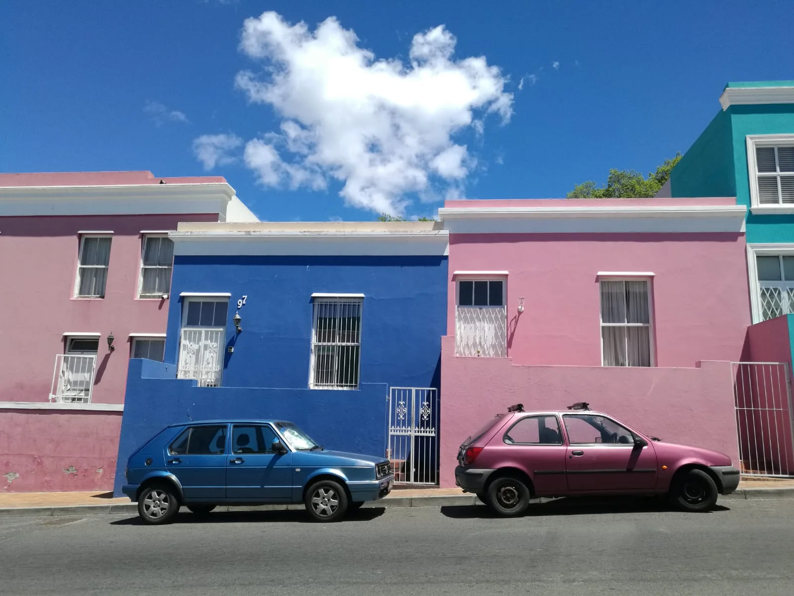 Des maisons roses et bleues sous un ciel ensoleillé.